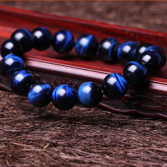 Blue tiger eye gemstone bead bracelet on carved wooden stand with textured natural background