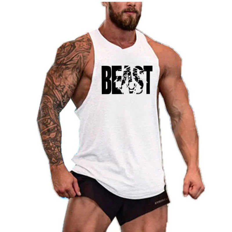 Muscular man wearing white sleeveless gym tank top with 'BEAST' text and black shorts, showcasing tattoos and fitness