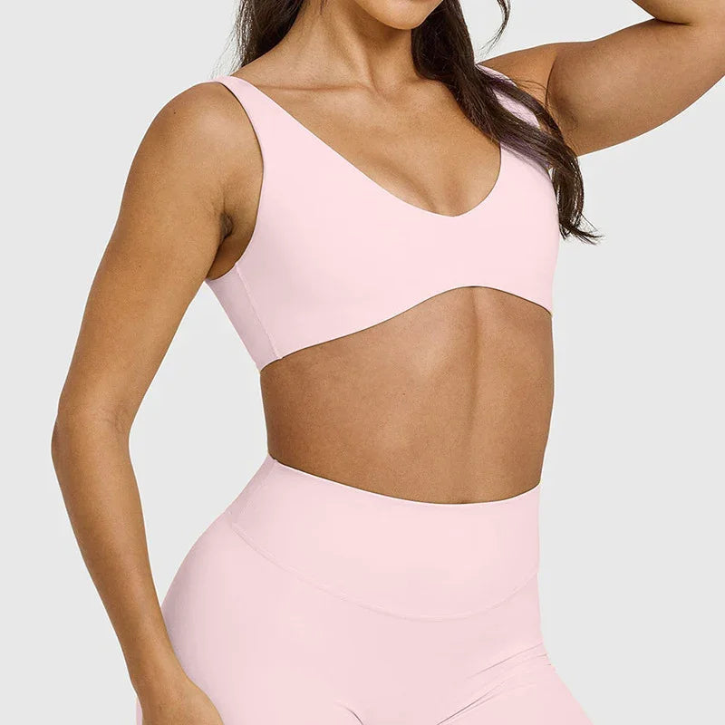 Woman wearing light pink sports bra and high-waisted leggings activewear set